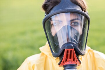 Person in overalls and gas mask call to save the planet while standing on green field on sunset....