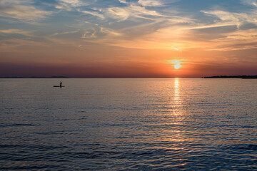 Silhuette of girl on sup board with beautiful colored sunrise background, Zaton, Croatia