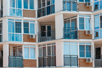 Residential building with glazed windows and balconies on a sunny day.