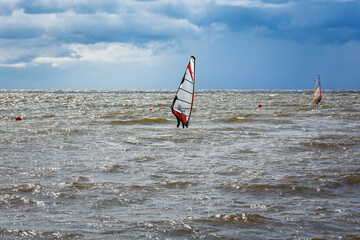 Naklejka premium Windsurfing.Windsurfers have fun on the water against a stormy sky.