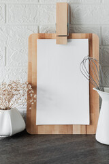 Blank paper mock-up in modern kitchen interior with white tile brick, utensils and wooden cutting...