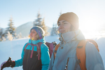 Two women with backpacks walk in the winter trekking