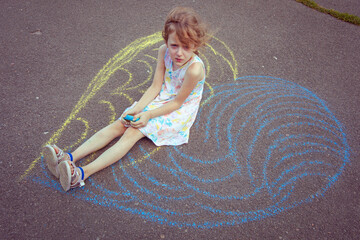 Child from Ukraine draws with chalk.