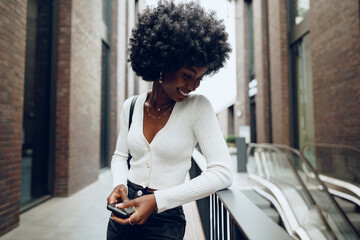 Portrait of young african woman with afro hairstyle smiling in urban background
