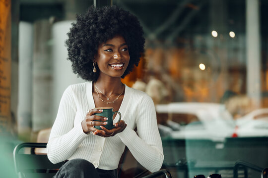 Young afro woman taking break and drinking coffee in cafe