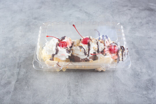 A view of a banana split inside a closed clamshell plastic container.