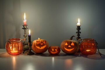 halloween pumpkins with burning candles on white table