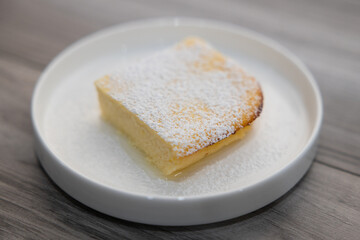 Italian lemon ricotta dessert cake with homemade limoncello and powdered sugar on white plate