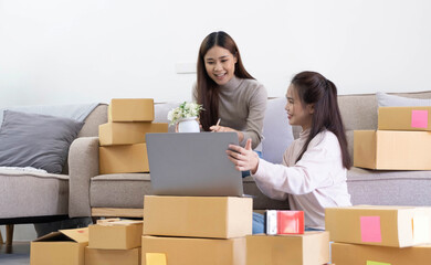 Startup small business owner working with computer at workplace. Freelance two woman seller check product order. Packing goods for delivery to customer. Online selling. E-commerce. Online Shopping