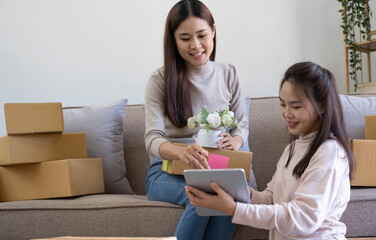 Startup small business owner working with computer at workplace. Freelance two woman seller check product order. Packing goods for delivery to customer. Online selling. E-commerce. Online Shopping