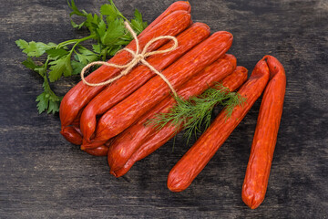 Bundle of kabanos sausages and fresh greens on black surface