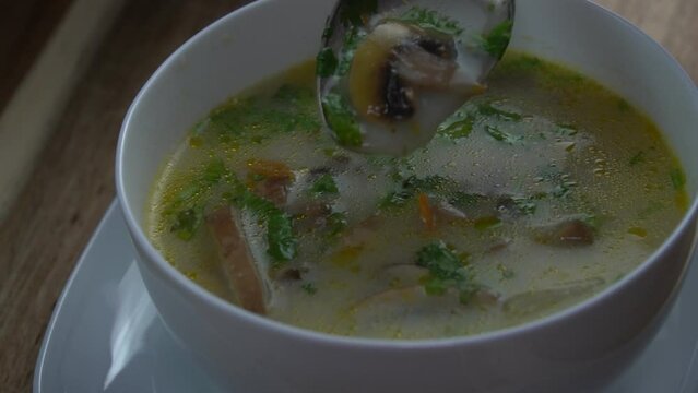 Mushroom soup in a bowl, stirring with a tablespoon