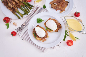 Tasty eggs Benedict, hollandaise sauce and aspargus covered with bacon