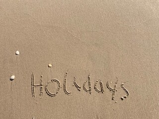 on the beach is carved with letters in the smooth sand the writing holidays