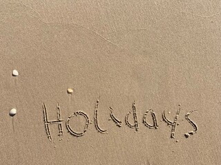 on the beach is carved with letters in the smooth sand the writing holidays