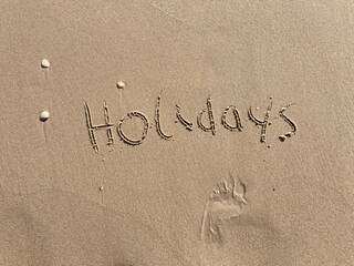 on the beach is carved with letters in the smooth sand the writing holidays