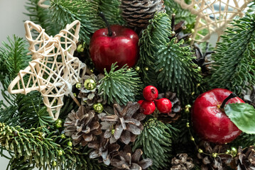 Christmas decor of fresh fir branches, dried pine cones, red apples and wicker stars