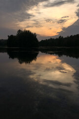 Dramatic sky with sun shines through gray clouds reflected at lake water at night