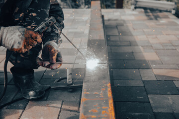 A worker works with metal welding at a construction site.