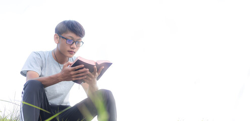 Handsome boy christian in glasses reading Bible in morning. focus on face. Copy space for your individual text.