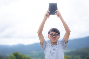 Happy young christian in glasses lift up Bible in morning. focus on face. Copy space for your...