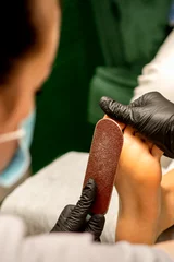 Foto auf Leinwand Pedicurist rubbing heel with a special grater on pedicure treatment in a beauty salon © okskukuruza