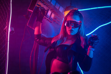 Young girl in the leather jacket is posing in neon lights.