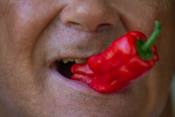 man eating chili pepper closeup view
