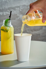 Fresh lemonade poured into a paper cup. Gray background.