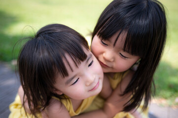 夏の芝生の公園で元気に遊ぶ姉妹