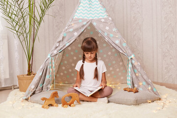 little girl with braids wearing white t shirt posing in wigwam © sementsova321
