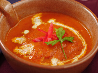 Roasted carrot soup in decorative brown bowl with cream drizzled on top