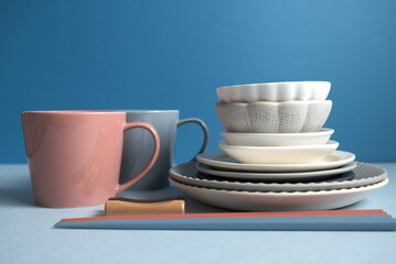 積み重ねた皿と箸とカップと青背景の中央配置の写真