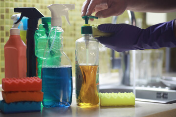 A bottle with an environmentally friendly dishwashing detergent on the background of a housewife washing dishes