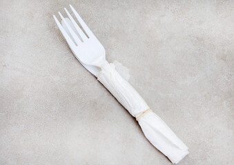 Take-Away plastic cutlery wrapped in serviette on mottled grey table with copy space