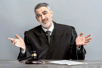 Judge spreads his arms to the side with disappointment judge's gavel. Law Lord wearing gown using a...