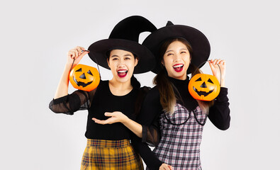 Asian woman in holloween costume witch black hat and carrying the pumkin lantern on white background.