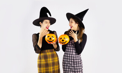 Two asian women in holloween costume with black witch hat holding the pumkin lantern on white background.