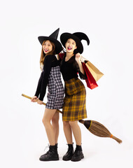 Halloween concept, young asian women wearing witch hat holding broom and shopping bags posing on white background.
