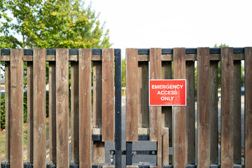 Shallow focus of a red Emergency Access Sign seen on a gated entrance to a hospital facility.