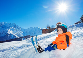 Smiling Boy with ski ready for skiing school sit in snow