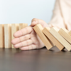 Businesswoman stops hands falling over domino to stop risk continuously, Continuous damage reduction, Stop business domino failures concept.