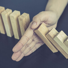 Businesswoman stops hands falling over domino to stop risk continuously, Continuous damage...