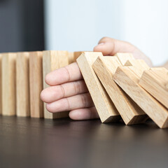Businesswoman stops hands falling over domino to stop risk continuously, Continuous damage...