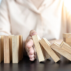 Businesswoman stops hands falling over domino to stop risk continuously, Continuous damage...