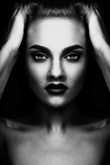 Abstract, fine art, sci-fi and fashion concept. Beautiful and sexy looking woman portrait. Model holding her hands on head and looking to camera. Mirror blending effect applied. Black and white image