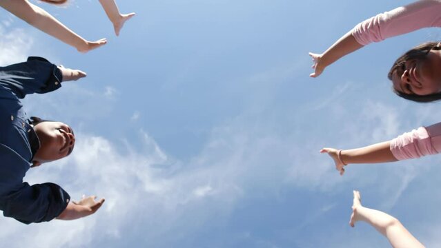 Bottom view of diverse classmates put hands together in circle and raise outdoors