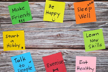 Healthy lifestyle and physical, emotional, mental social and intellectual wellbeing concept. Colorful sticky notes reminder set in wooden background with copy space.