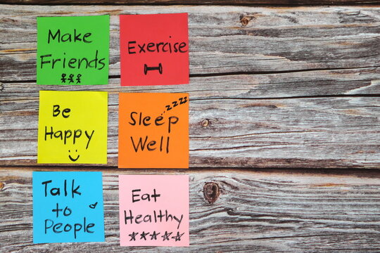Healthy lifestyle and physical, emotional, mental social and intellectual wellbeing concept. Colorful sticky notes reminder set in wooden background with copy space.