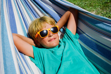 Boy with orange sunglasses lay in hammock close portrait